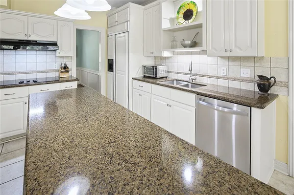 a kitchen with granite countertop white cabinets and stainless steel appliances