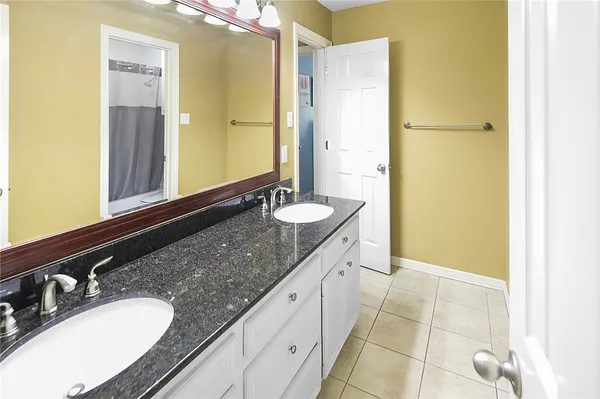 a spacious bathroom with a granite countertop double vanity sink a mirror and a shower