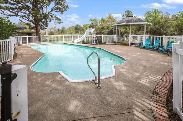a view of a swimming pool with a patio and a yard