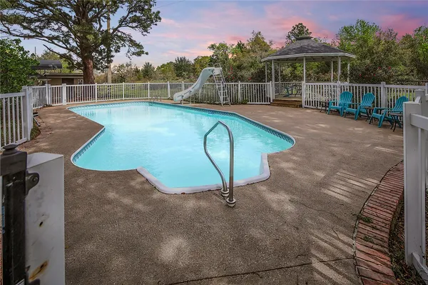 a view of a backyard with swimming pool and sitting area