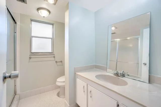 a bathroom with a granite countertop sink a toilet and a mirror