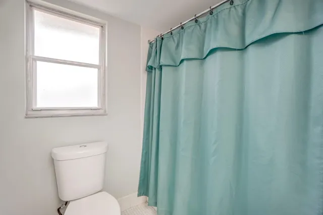 a white toilet sitting next to a shower curtain