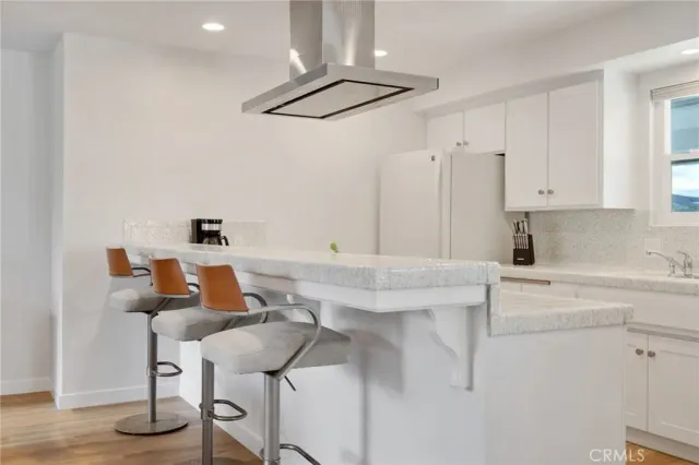 a kitchen with stainless steel appliances kitchen island a table chairs in it and white cabinets