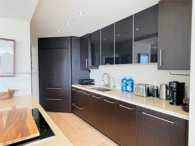 a kitchen with stainless steel appliances a sink dishwasher a refrigerator a stove and wooden cabinets