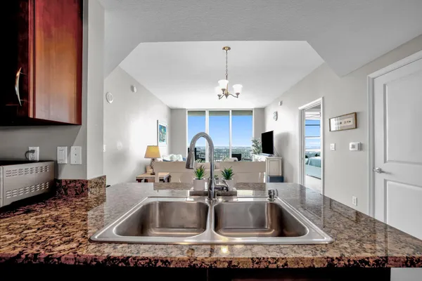 a kitchen with kitchen island granite countertop a sink and refrigerator