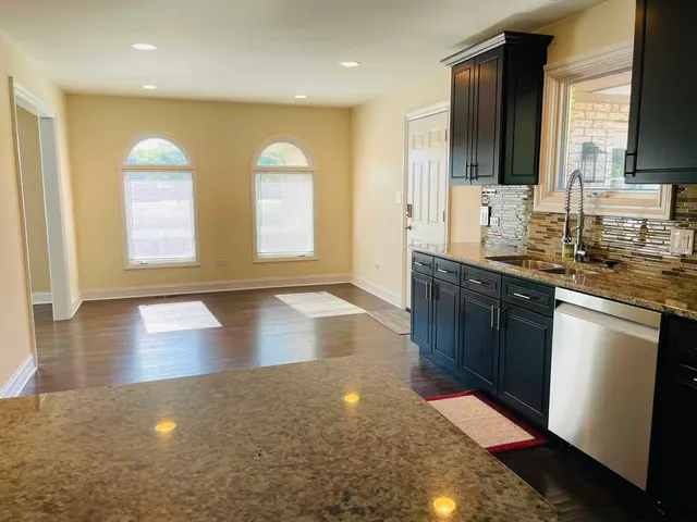 a kitchen with stainless steel appliances granite countertop a sink a stove cabinets and wooden floor