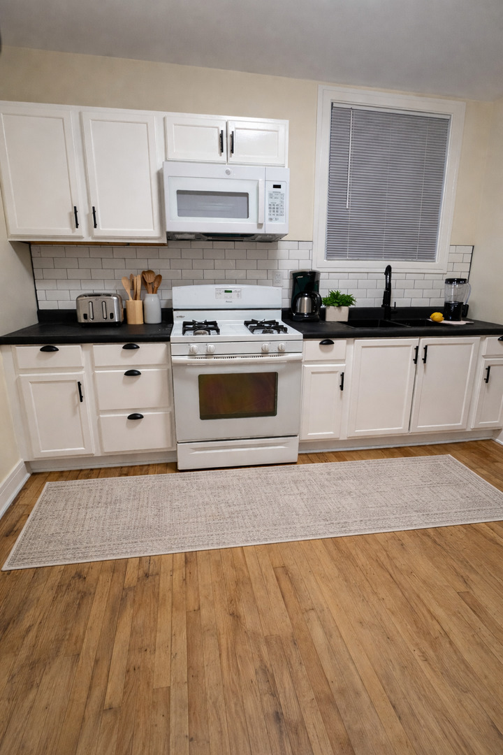 610 East 74th Street, Unit 2B Chicago, IL 60619 - Photo 4 of 7 a kitchen with stainless steel appliances granite countertop a stove a sink and white cabinets