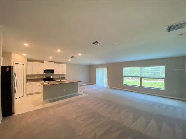 a kitchen with stainless steel appliances kitchen island granite countertop a stove top oven a sink and a refrigerator