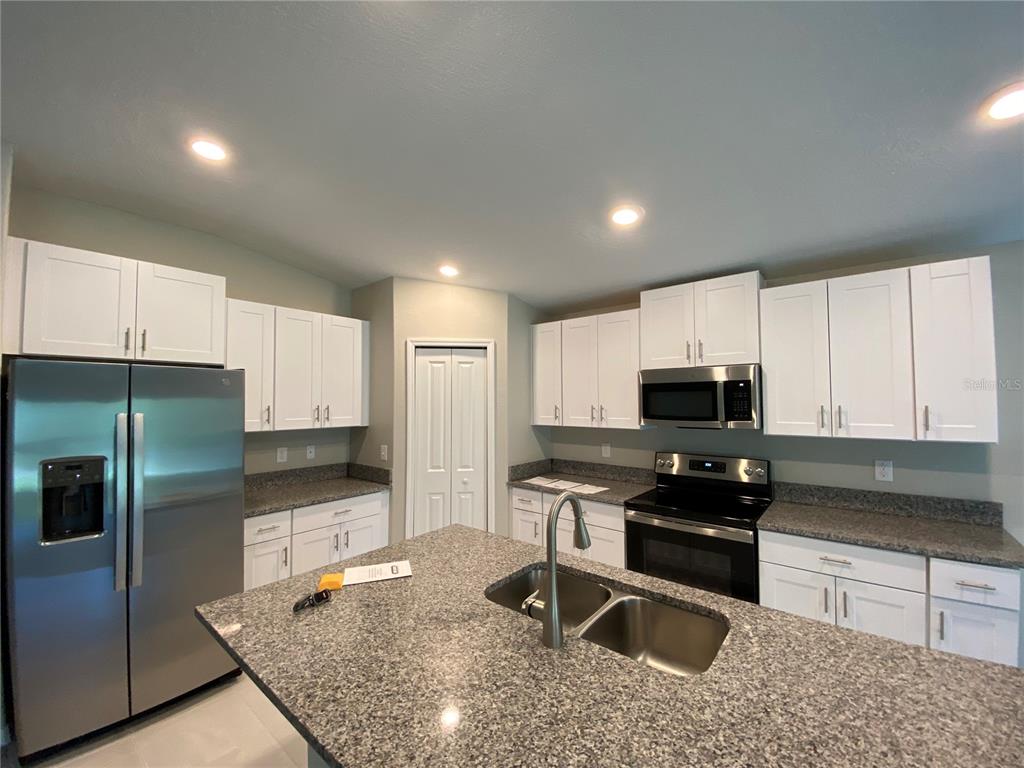 2530 Southwest 167th Loop Ocala, FL 34473 - Photo 6 of 31 a kitchen with kitchen island granite countertop a sink a stove and refrigerator
