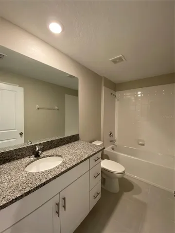 a bathroom with a granite countertop sink a toilet and bathtub