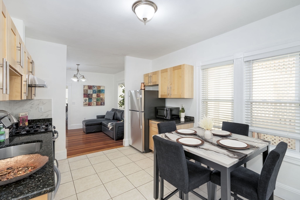 122 Brook Road, Unit 2 Quincy, MA 02169 - Photo 2 of 11 a kitchen with a table chairs stove and refrigerator