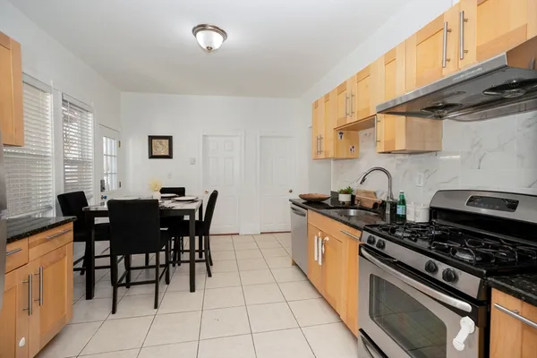 a kitchen with stainless steel appliances a table chairs and a stove top oven
