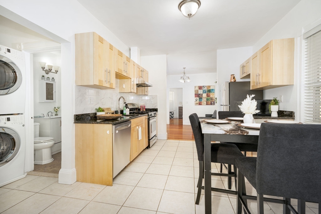 122 Brook Road, Unit 2 Quincy, MA 02169 - Photo 4 of 11 a kitchen with a dining table chairs and a refrigerator