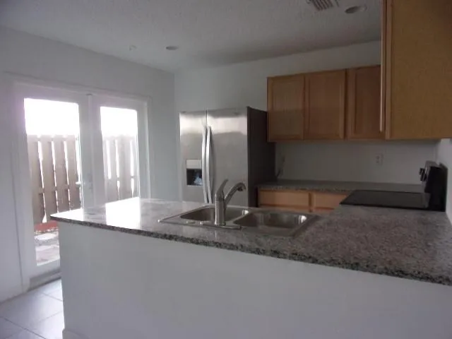 a kitchen with kitchen island granite countertop a sink and a refrigerator