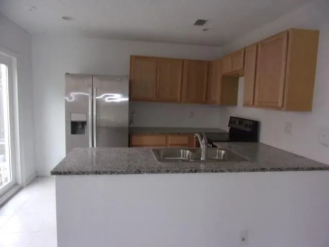 a kitchen with granite countertop a sink a counter top space cabinets and stainless steel appliances