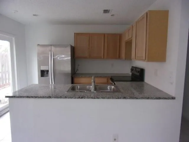a kitchen with stainless steel appliances granite countertop a sink a refrigerator and a granite counter tops