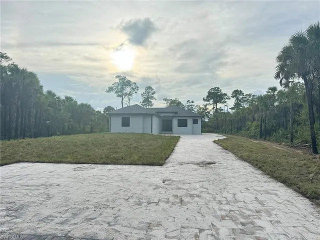 a large white kitchen with stainless steel appliances kitchen island granite countertop a large cabinets a sink and a counter top space