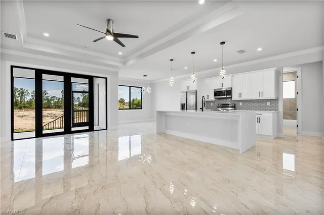 a large white kitchen with stainless steel appliances granite countertop a lot of counter space and wooden floors