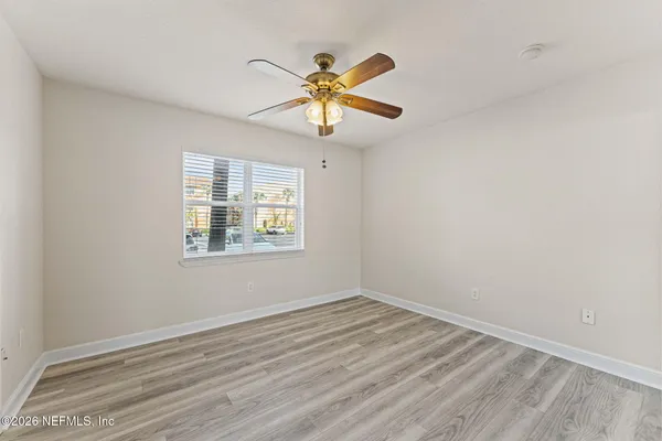 a view of a room with wooden floor fan and windows