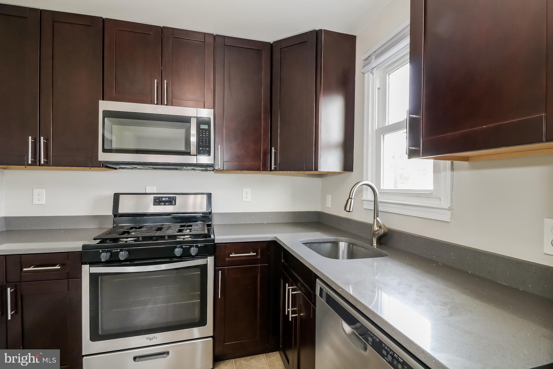 5674 Leiden Road Baltimore, MD 21206 - Photo 7 of 14 a kitchen with granite countertop a sink stove and microwave