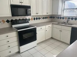 a kitchen with granite countertop white cabinets and stainless steel appliances