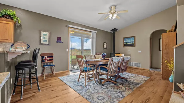 a kitchen with stainless steel appliances granite countertop a refrigerator a stove a sink a dining table and chairs with wooden floor