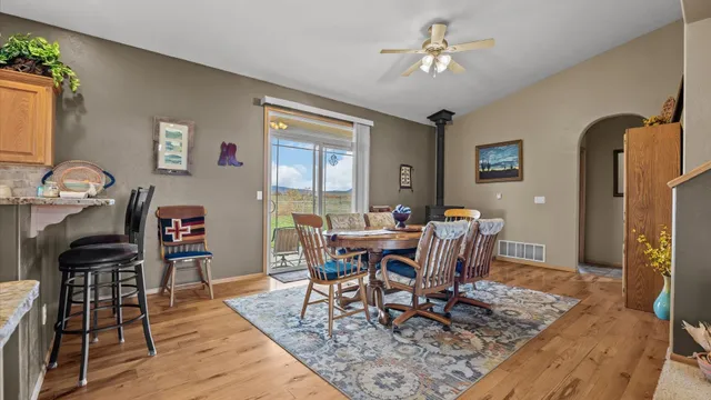 a kitchen with stainless steel appliances granite countertop a refrigerator a stove a sink a dining table and chairs with wooden floor