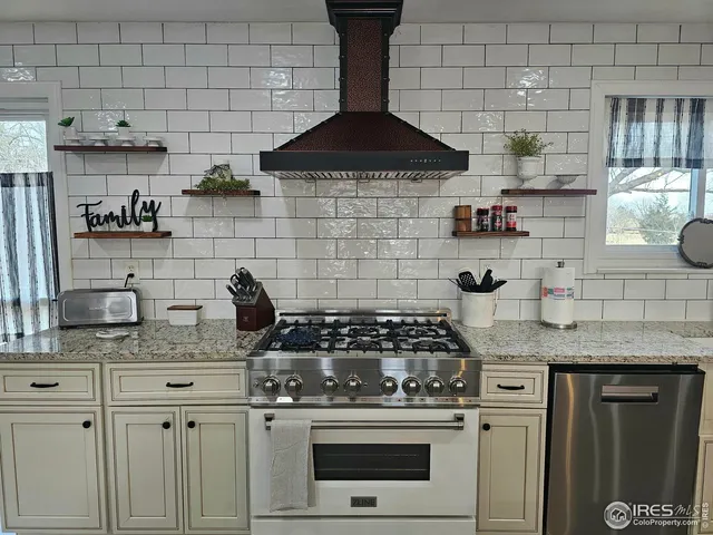 a kitchen with granite countertop a stove a sink dishwasher and cabinets