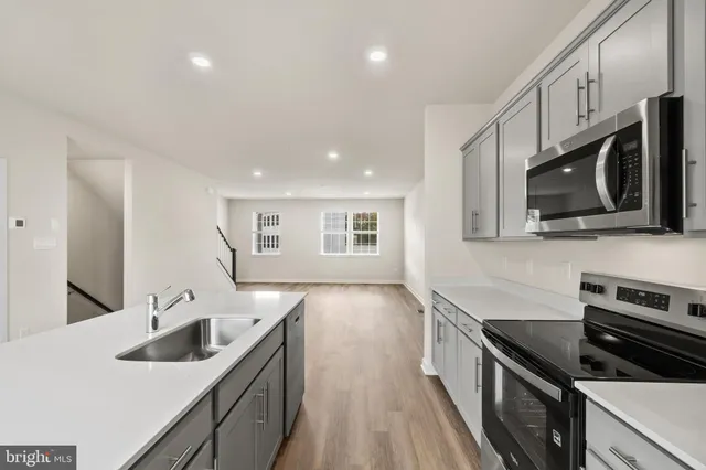 a kitchen with stainless steel appliances granite countertop a sink and stove top oven with wooden floor