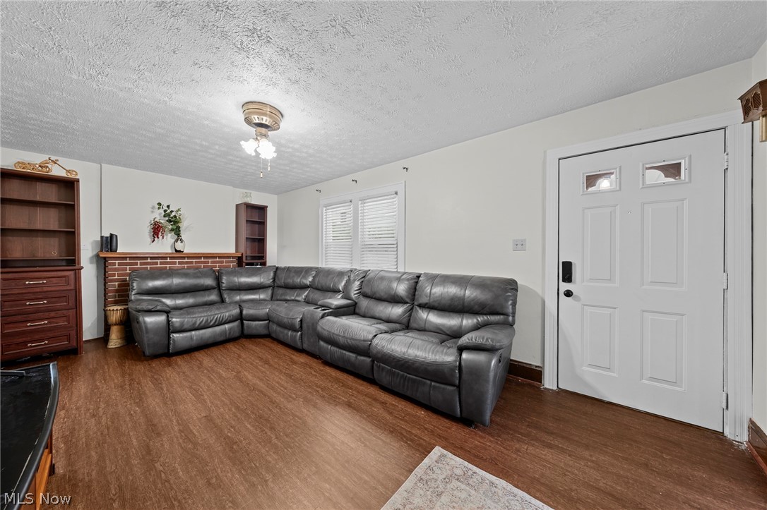 819 Keeney Street Akron, OH 44310 - Photo 5 of 24 Spacious living area featuring wood-finish flooring, a brick fireplace, and a white paneled entry door with decorative glass inserts