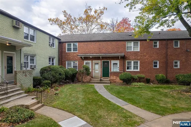 a view of a brick house with a yard and plants