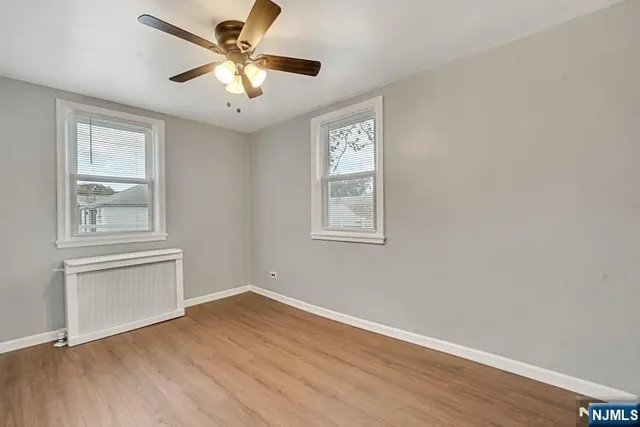a view of an empty room with window and wooden floor