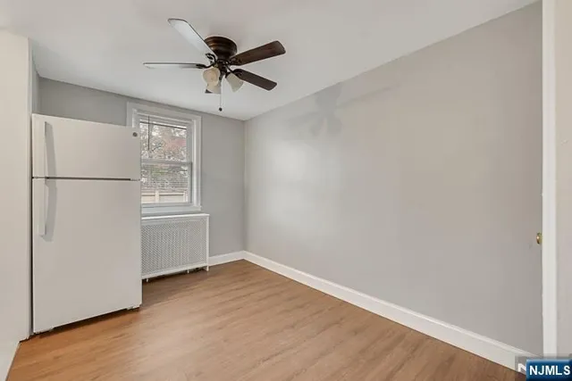 a view of empty room with wooden floor and ceiling fan