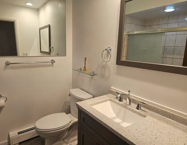 a bathroom with a granite countertop toilet sink and mirror