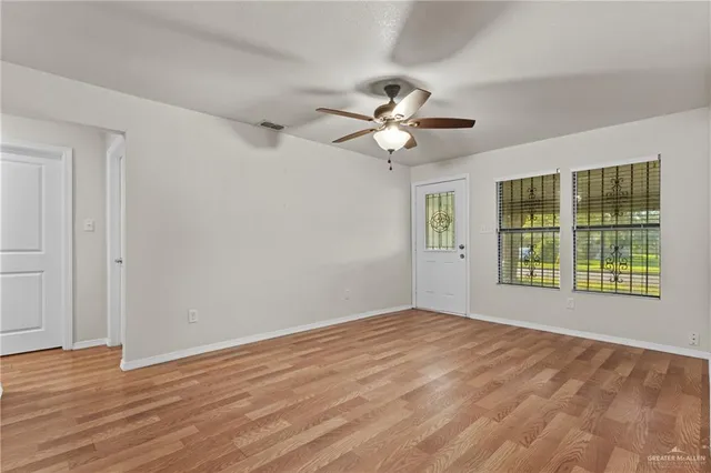 a view of an empty room with a window and wooden floor