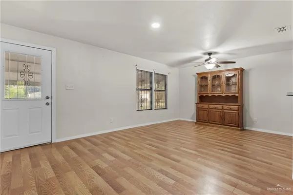 a view of an empty room with a window and wooden floor