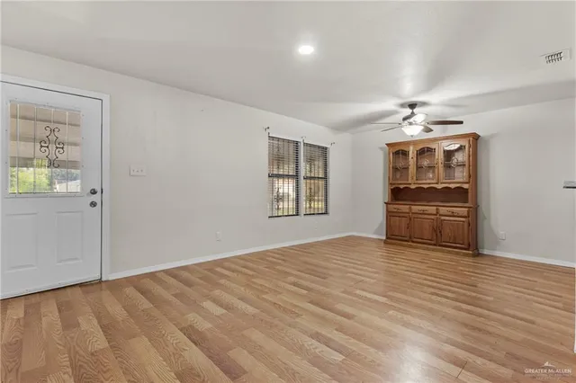 a view of an empty room with a window and wooden floor