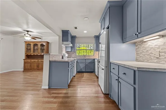 a large kitchen with stainless steel appliances kitchen island granite countertop a large counter top and wooden floors