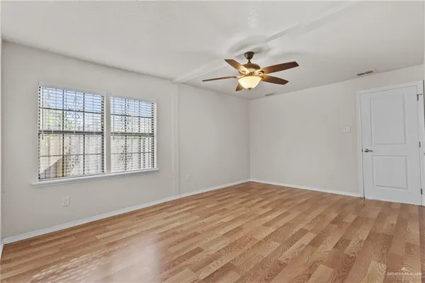 a view of empty room with wooden floor and fan