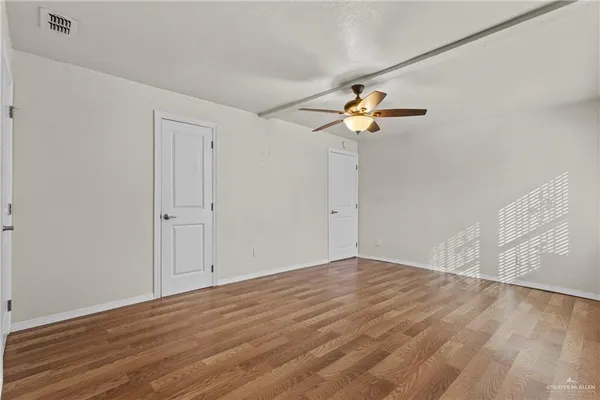 a view of a room with wooden floor and a ceiling fan