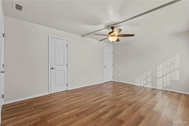 a view of a room with wooden floor and a ceiling fan