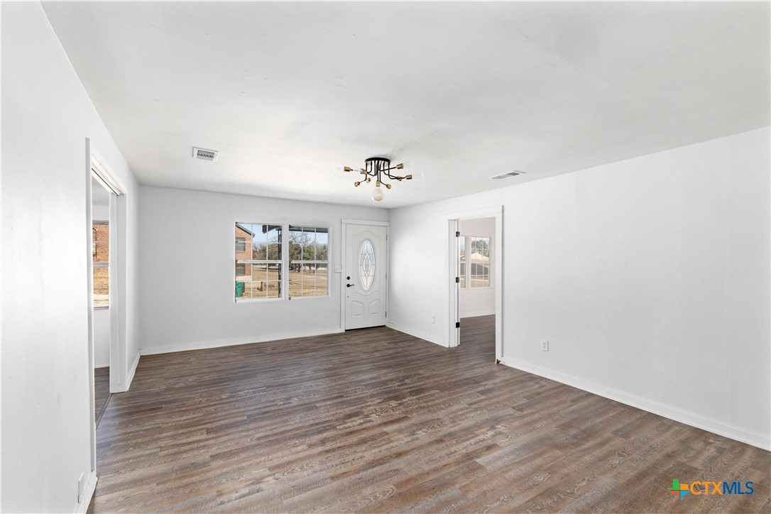 104 East Whitney Street Hamilton, TX 76531 - Photo 15 of 24 an empty room with wooden floor chandelier and windows