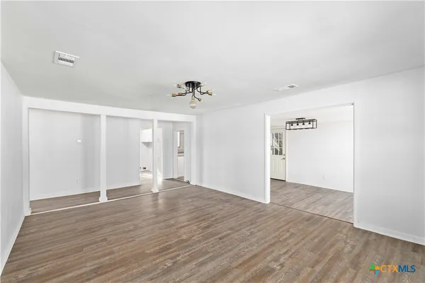 a view of empty room with wooden floor