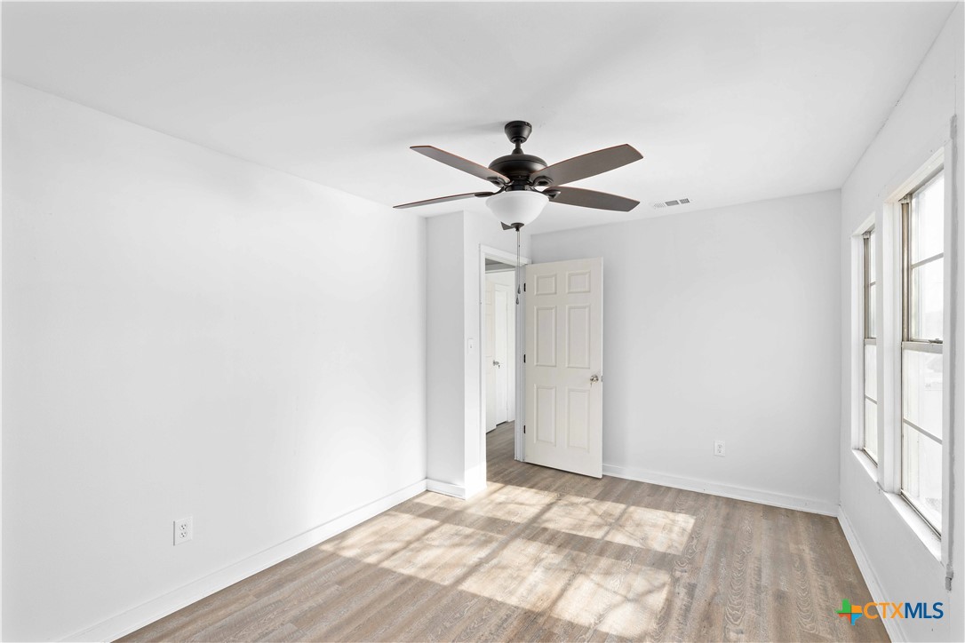 104 East Whitney Street Hamilton, TX 76531 - Photo 3 of 24 an empty room with wooden floor and windows