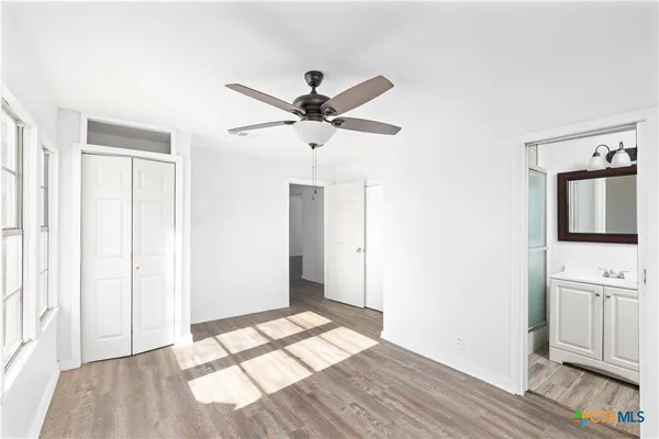 a view of empty room with wooden floor and fan