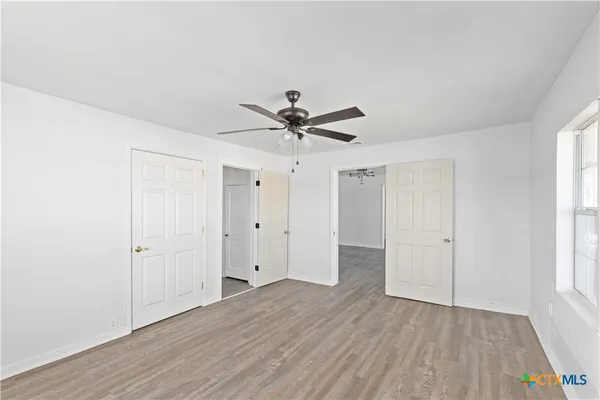 an empty room with wooden floor and windows