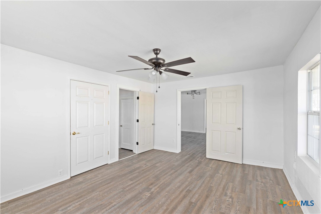 104 East Whitney Street Hamilton, TX 76531 - Photo 9 of 24 an empty room with wooden floor and windows