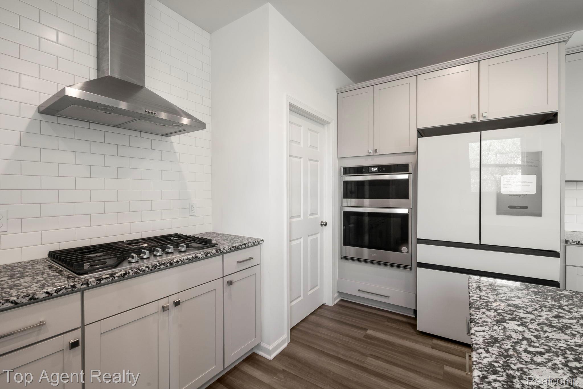 63770 Dequindre Road Washington, MI 48095 - Photo 22 of 61 Contemporary kitchen featuring a stainless steel range hood, subway tile backsplash, gas cooktop, light-toned cabinetry, and speckled countertops