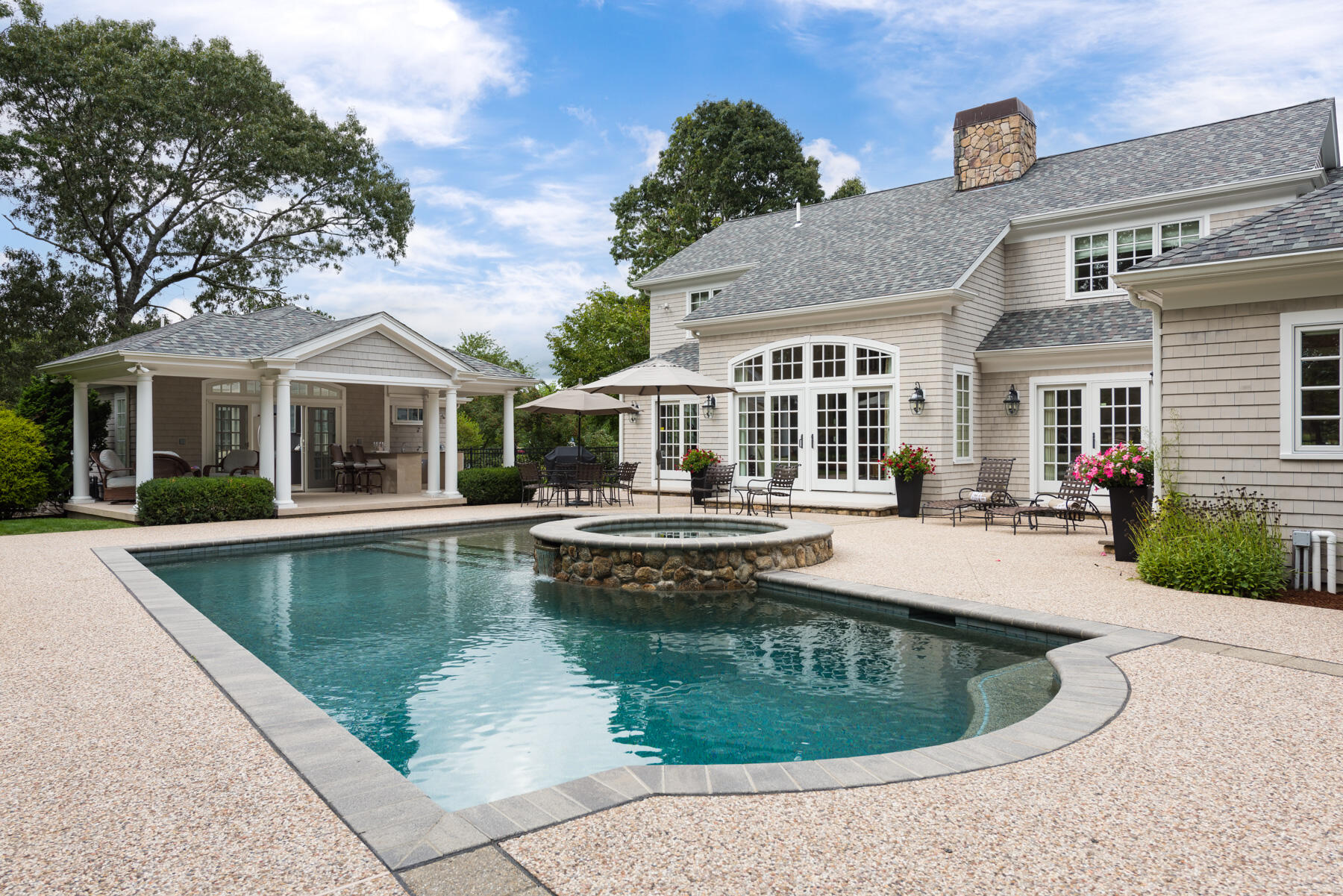 a view of a white building with a large pool and large trees