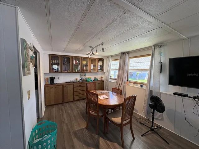 a kitchen with stainless steel appliances kitchen island granite countertop a dining table chairs and a refrigerator